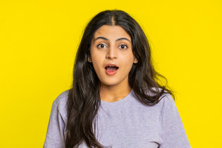 Oh my God, Wow. Excited amazed winner woman raising hands in surprise looking at camera with big eyes, shocked by sudden victory celebrating success achievement good news. Girl on yellow backgroundの写真素材