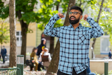 Indian young man shouting celebrating success winning goal achievement good news lottery jackpot casino luck victory career outdoors. Hispanic guy on urban city street. Town lifestyles. Horizontalの写真素材