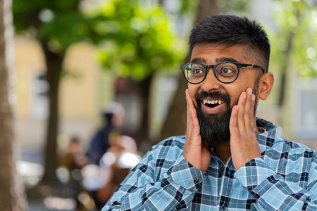Oh my God, Wow. Indian bearded man looking surprised at camera with big open eyes shocked by victory game winning, lottery goal achievement, good news outdoors. Hispanic guy on urban city streetの写真素材