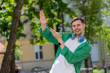 Cheerful rich happy man showing wasting throwing money around hand gesture, more tips earnings, big profit, win lottery, share, celebrate outdoors. Young guy male traveler standing on city street.の写真素材