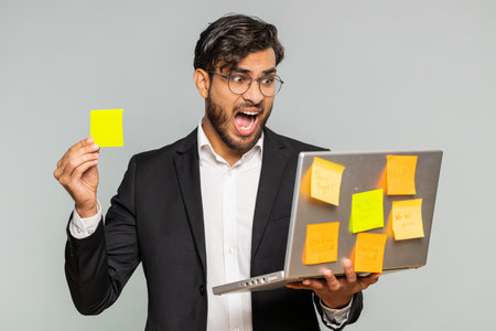 Exhausted Indian businessman with pasted sticker notes use laptop computer have concentration...