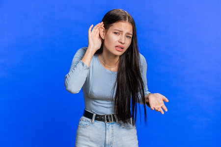 I cant hear you. What. Young woman trying hear you, looking confused and frowning, keeping arm near...