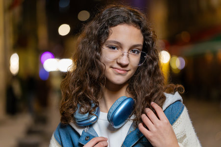Portrait of happy pretty young woman smiling friendly glad expression looking at camera dreaming resting relaxation feel satisfied good news outdoors. Lovely girl tourist in urban city street at nightの写真素材
