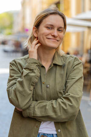 Portrait of happy young woman face smiling friendly glad expression looking at camera resting relaxation feel satisfied good news outdoors. Pretty blond adult girl tourist traveler on city street.の写真素材