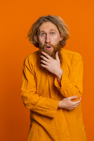 Oh my God, Wow. Excited amazed redhead man raising hands in surprise looking at camera with big eyes shocked by sudden victory celebrating win success achievement good news. Guy on orange backgroundの写真素材