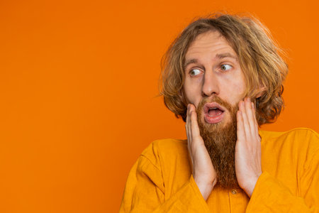 Oh my God Wow. Excited amazed winner man raising hands in surprise looking at camera with big eyes shocked by sudden victory celebrating success achievement good news. Redhead guy on orange backgroundの写真素材