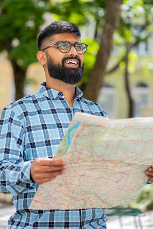 Young man tourist exploring city street, sightseeing holding paper map, check direction searching...