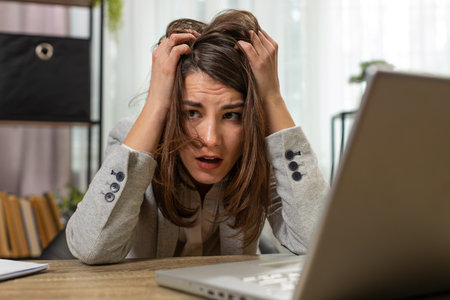 Tired sleepy young businesswoman sitting at home office table with laptop overworked lazy bored lady...