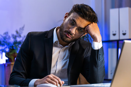 Tired Indian businessman feeling worried about financial problem, stress at home office workplace. Indian freelancer broker man frustrated thinking of money debt, budget loss, bankruptcy. Overworkingの写真素材