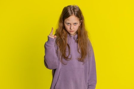 Displeased young cute redhead school girl gesturing hands with irritation and displeasure, blaming scolding for failure asking why this happened. Preteen female child kid on yellow backgroundの写真素材