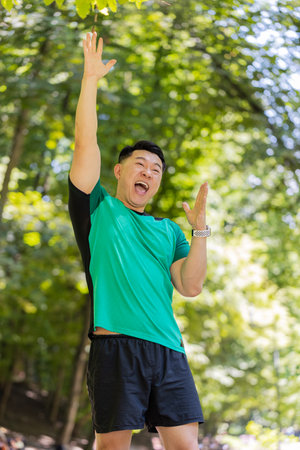 Athletic fit runner guy celebrate success win scream rejoices triumph victory marathon race. Workout cardio training in sunny park. Asian young man enjoy healthy lifestyle. Active sportsman motivationの写真素材
