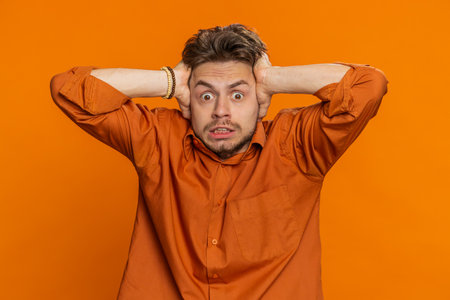 Scared stressed bearded man terrified about danger problems, suffering phobia, anxiety disorder, expresses fear, waving no, insecure, stress, panic. Depressed fearful guy on orange studio backgroundの写真素材