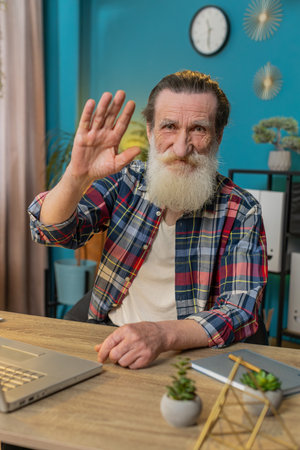 Hello. Happy senior man employee waves hand hi gesture greeting welcomes someone, online webinar,...