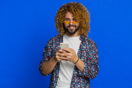 Caucasian man use smartphone typing post on web, browsing searching, addiction of social networks, showing positive application game feedback, recommends wifi cellular connection on blue background.の写真素材