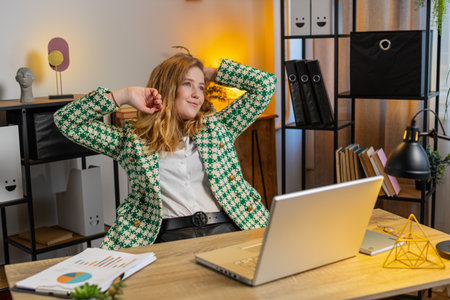 Happy Caucasian businesswoman relaxing at home office desk works on laptop and stretching arms after finishing work. Girl freelancer working online remote job. E-learning, browsing internet on netbookの写真素材