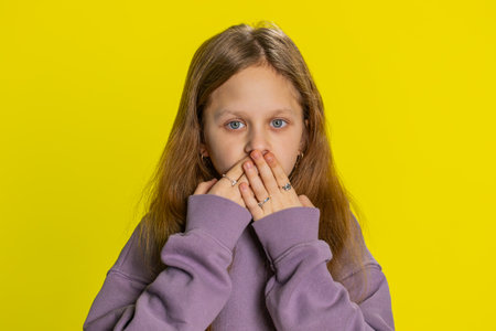 I will not say anything. Frightened child girl kid closing mouth with hands, looking intimidated...