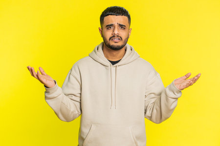 What. Why. Angry man raising hands in indignant expression, asking reason of failure, demonstrating disbelief irritation by troubles. Young guy isolated on yellow studio backgroundの写真素材