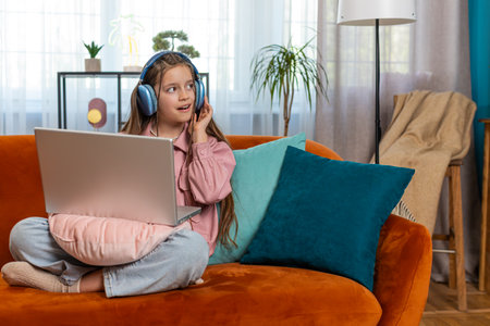 Caucasian preteen girl in headphones using laptop listens to music or lesson, distance learning....