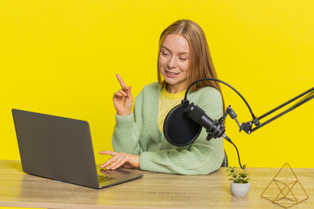 Happy excited woman blogger at table recording podcast, giving workshop, webinar. Adult girl...
