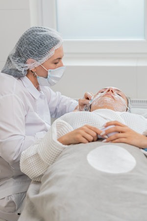 Beauty anti-aging injections biorevitalization face mesotherapy. Cosmetologist doctor making needle hyaluronic injections syringe into skin of young woman girl. Lifting procedure therapy in clinicの写真素材