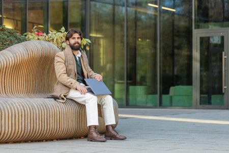 business man freelancer closes laptop screen finishing working online distant job browsing website chatting, looking at camera. guy use notebook, sends messages on downtown city streetの写真素材
