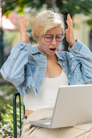 Upset young woman tourist using laptop computer typing browsing, loses becoming surprised sudden...