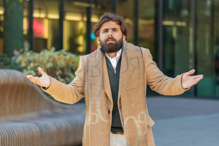 Doubtful sad frustrated man tourist shrugging shoulders dont know answer incertitude gesture uncertain reaction on difficult question. Confused businessman feel disappointment on city streetの写真素材