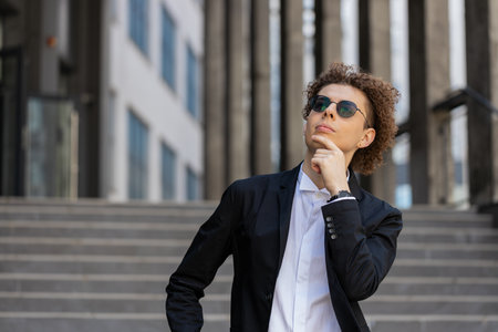 Portrait of Caucasian puzzled businessman professional standing outdoors deep in thoughts thinking recollecting memory creating plan. Handsome man in formalwear and sunglasses on downtown city street.の写真素材