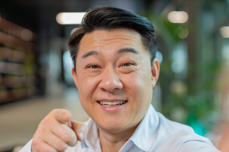 Closeup portrait of happy Chinese businessman boss shake hand hi gesture greeting welcomes someone,...