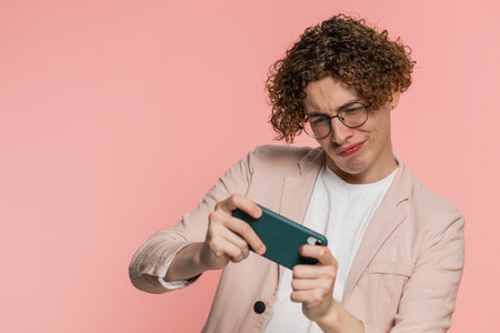 Happy excited Caucasian young man with curly hair playing racing drive simulator shooter video games...