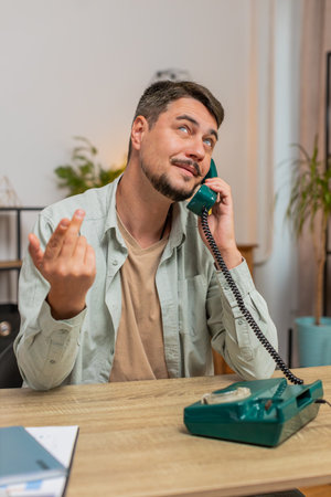 Caucasian man freelancer working, talking with client on retro old-fashioned wired telephone at home office table. Salesman in casual clothes. Remote distant job. Employment occupation. Vertical.の写真素材