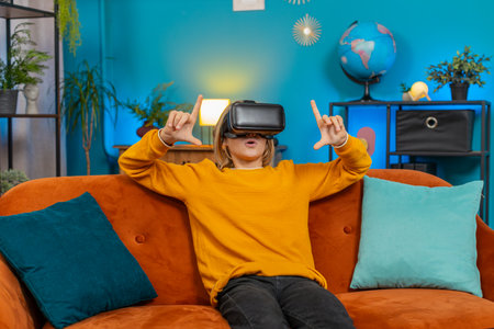 Teenager boy plays virtual reality game at home couch living room. Enthusiastically waves hands...