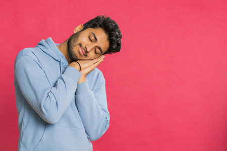 Tired exhausted young man yawning, sleepy inattentive feeling somnolent lazy bored gaping suffering from lack of sleep, falling asleep. Guy isolated on red studio backgroundの写真素材