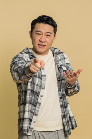Happy Asian middle-aged man smiling excitedly and pointing forward to camera, choosing lucky game...