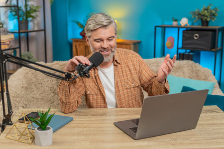 Caucasian mature man blogger speaking into studio microphone interacting with viewers subscribers...