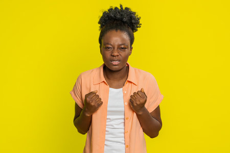 Upset frustrated annoyed African American woman raising hands in indignant expression, quarreling, asking reason of conflict, why such stubborn. Young adult Black girl isolated on yellow backgroundの写真素材