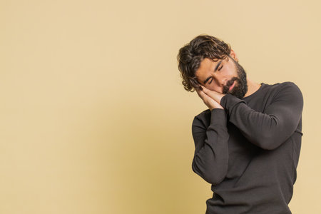 Tired overworked young Lebanese man sleepy inattentive feeling somnolent lazy bored gaping suffering from lack of sleep falling asleep. Exhausted lazy Indian guy isolated on studio beige backgroundの写真素材