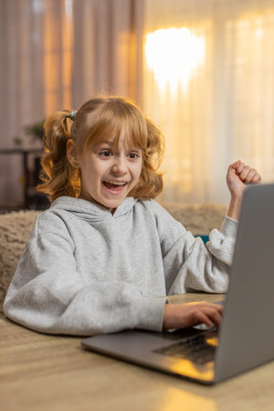 Young girl looking at laptop screen typing keyboard, learning programming online with great...