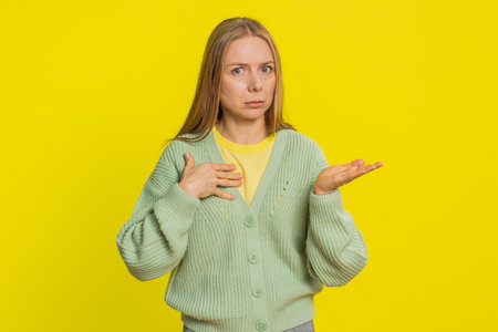 I am not guilty. Caucasian middle-aged woman pointing fingers herself ask say who me no thanks i do not need it, feels innocent, not her fault, fail mistake. Adult girl isolated on yellow backgroundの写真素材