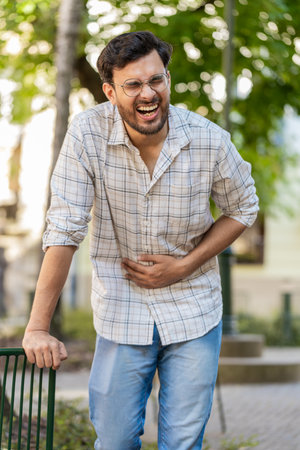 Arabian young man traveler feeling sudden strong abdominal stomach ache, gastritis problem. Upset tourist guy having symptom poisoning diarrhea indigestion peptic ulcer pancreatitis on city street.の写真素材