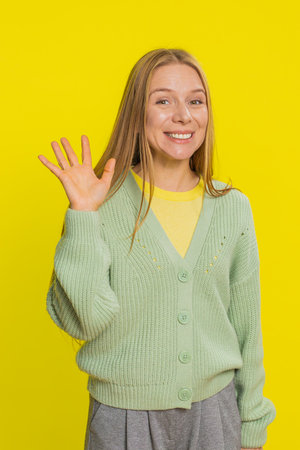 Young Caucasian woman smiling friendly at camera, waving hands gesturing hello greeting or goodbye...