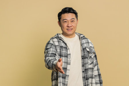 Friendly Asian Chinese middle-aged man outstretching hand to camera, offering handshake, greeting...