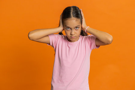 Frustrated annoyed irritated young cute school girl covering ears gesturing No, avoiding advice ignoring unpleasant noise loud voices. Preteen female child kid 10 years oldの写真素材