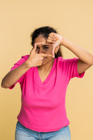 Indian influencer woman frames photo with hands creatively imagining perfect shot or blogging idea....