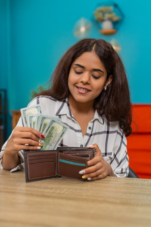Woman at home counts dollars cash placing bills into wallet feeling secure financial satisfaction...