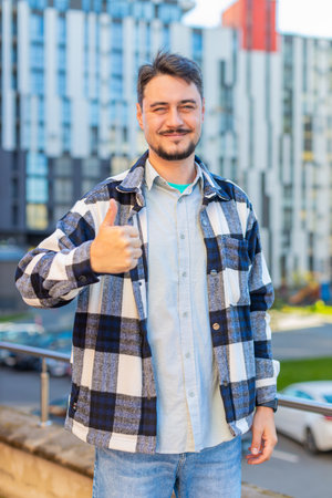 Like. Happy man raises thumb up agrees with something or gives positive reply recommends advertisement likes good idea feedback, celebrating success victory. Guy tourist standing on urban city street.の写真素材
