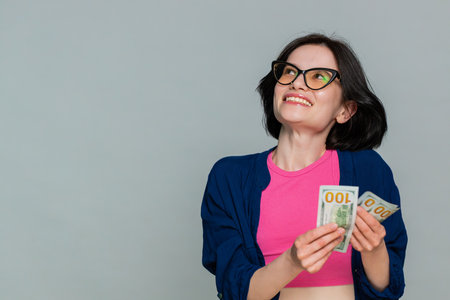 Woman smiles happily holding cash money in hands, clearly expressing financial success prosperity....