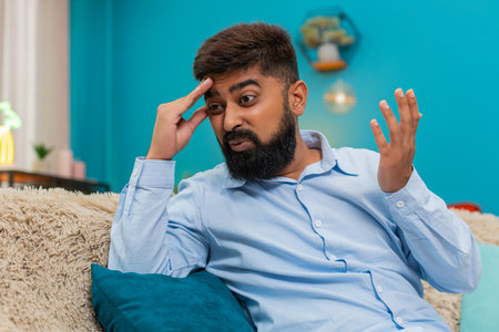 Man at home holds forehead facepalm after smartphone error looks disappointed regretful frustrated....
