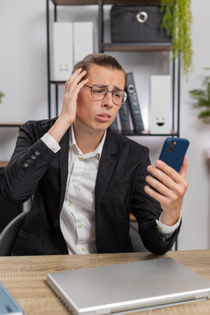 Caucasian young stylish man using smartphone typing browsing, loses becoming surprised sudden...