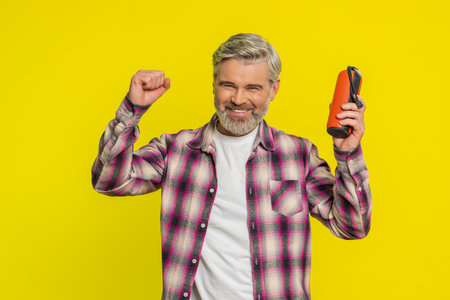 Mature man holds portable speaker listening music, dancing eagerly to favorite tunes, open delight....